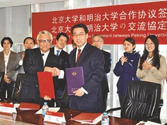 A firm handshake is exchanged upon signature of the agreement by Kosaku Dairokuno, Dean of the School of Political Science and Economics, and Fu Jun, Executive Dean of the School of Government.