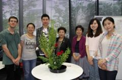 International exchange students trying out ikebana, using thunbery spirea, rose and leather fern