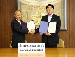 協定書に署名後、がっちりと握手を交わす福宮学長と松崎市長