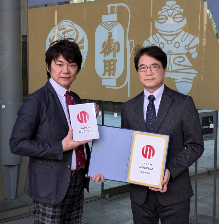 登録証とプレートを捧げ持つ石川幹人博物館長（情報コミュニケーション学部教授・右）と堀田秀吾副館長（法学部教授・左）