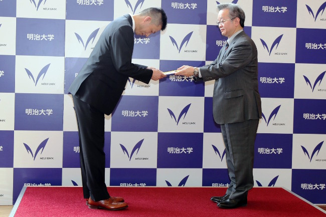井上理事長（右）から目録の贈呈を受ける小川副学長