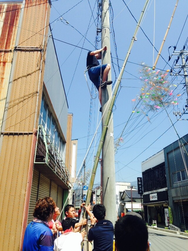七夕祭り：電柱に竹を立て掛ける学生