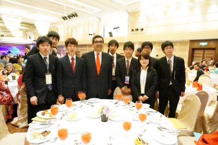 2013MSTクアラルンプール国際会議の懇親会の様子（DIAH副大臣（中央）と応用化学専攻の学生との記念写真、右から2番目が吉田君、3番目が小林さん）