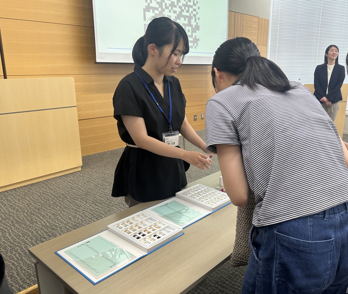 化粧品の原料のサンプルを見せながら質問に応じる秋野さん。化粧品業界に興味を抱く多くの中高生が秋野さんの周りに集まった