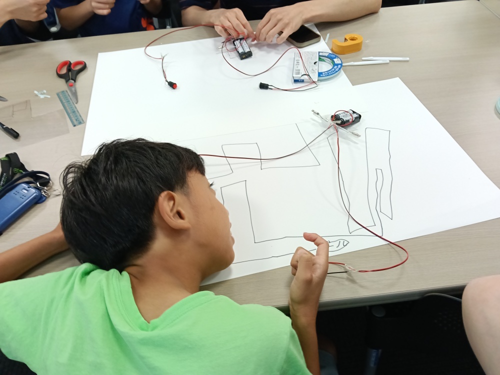 製作したブラシロボットが実際に動くのか注視する小学生